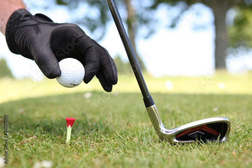 Closeup of a man placing a golf ball on the tee