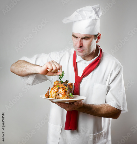 Chef holding plate with roasted chicken