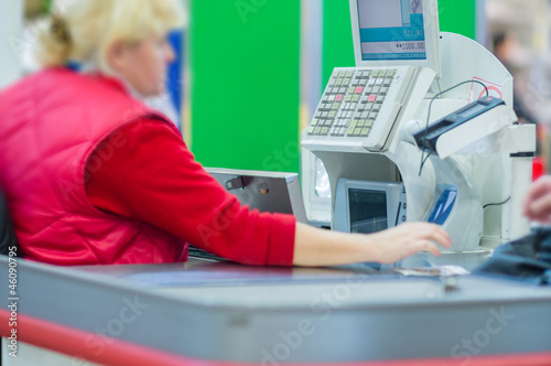 Cash-desk with cashier and terminal in supermarket. Serve custom