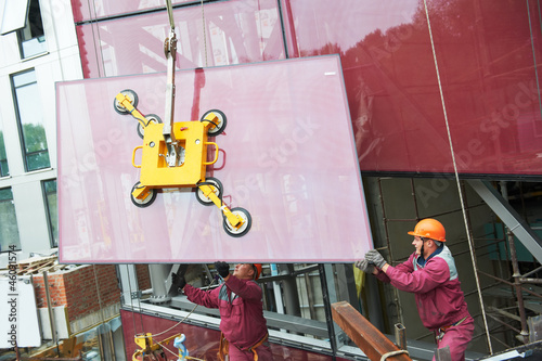 workers installing glass window on building