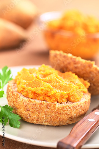 Sweet potato spread on wholegrain bun on plate with knife