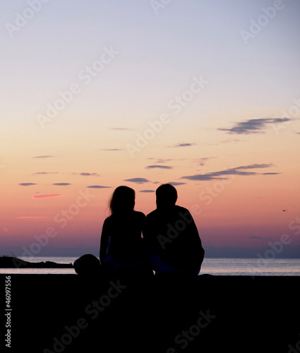 Couple watching the sunset by the sea