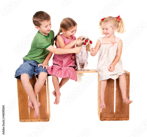 three kids feeding a dog a lolli pop
