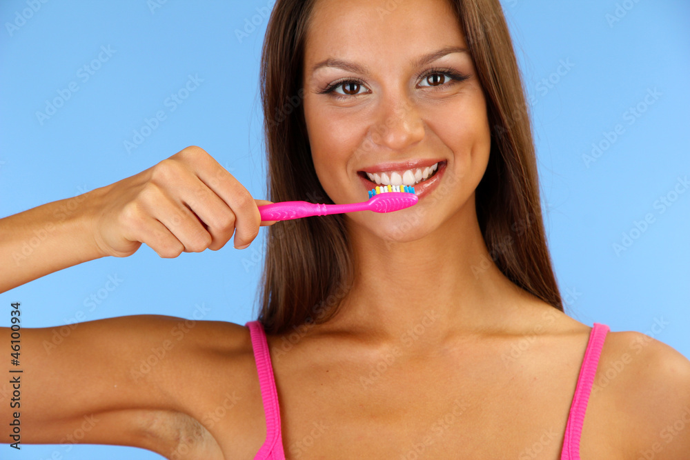 Beautiful young woman with toothbrush on blue background Beautiful young woman with toothbrush on blue background