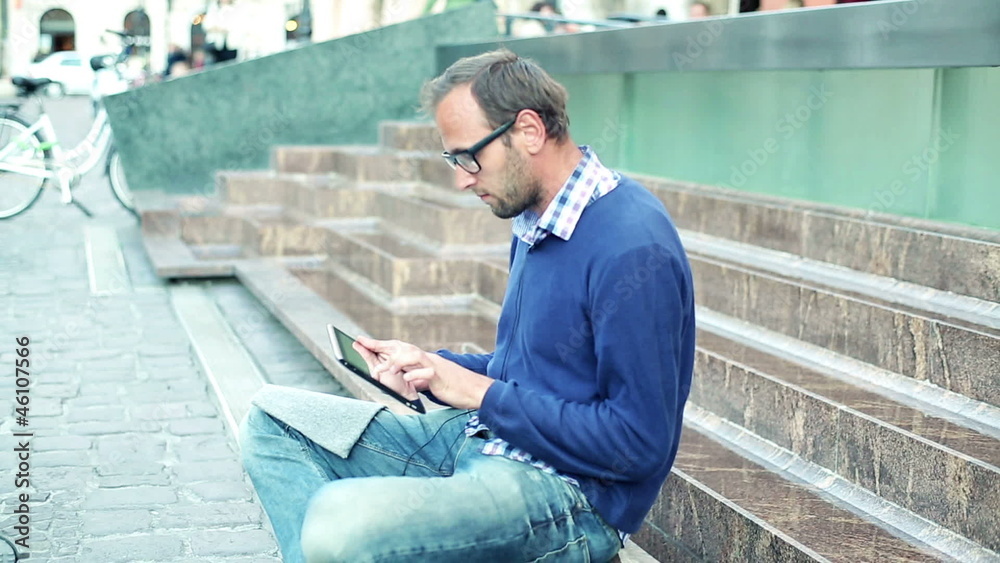 Young man with tablet computer sitting on the stairs, outdoors Young man with tablet computer sitting on the stairs, outdoors