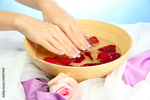 woman hands with wooden bowl of water with petals,
