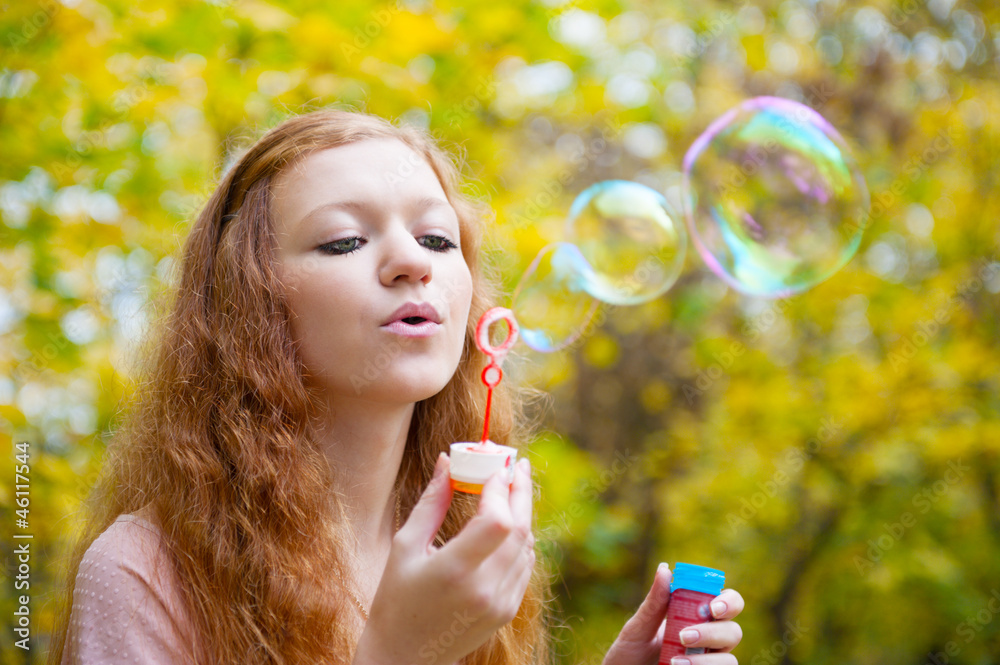 Young redhead girl blowing bubbles