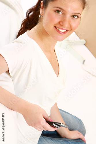 A smiling woman with a mobile phone on a sofa indoors photo