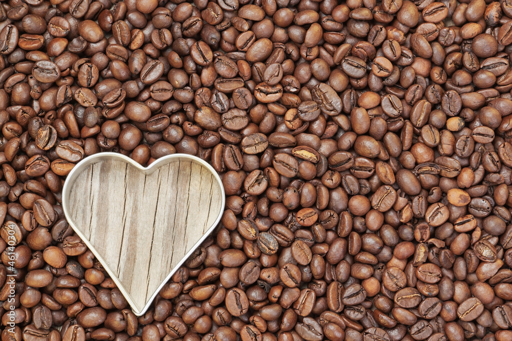 Heart shape in raw coffee beans. On a wooden texture. Heart shape in raw coffee beans. On a wooden texture.