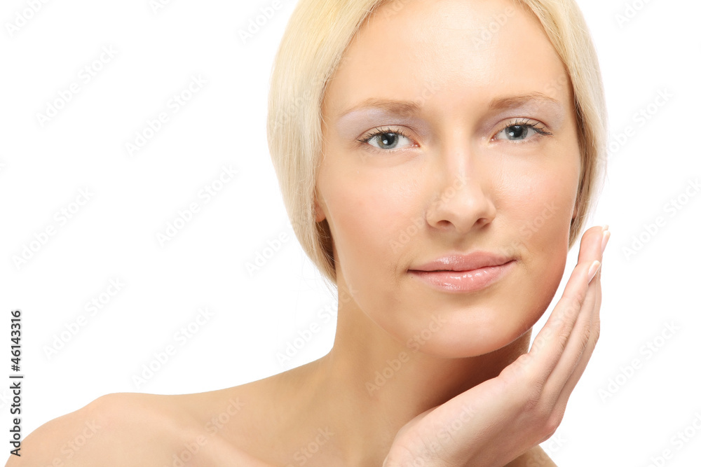 A beautiful woman is applying cream on her face over white