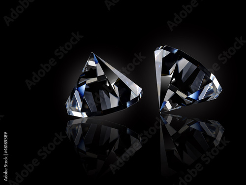 Two loose diamonds on black reflective surface