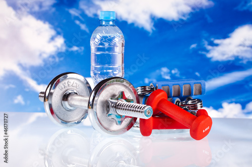 fitness dumbbells and water on blue sky background