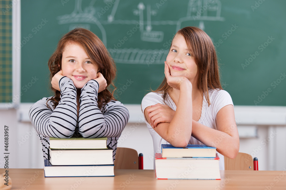 zwei schülerinnen mit büchern im klassenzimmer zwei schülerinnen mit büchern im klassenzimmer