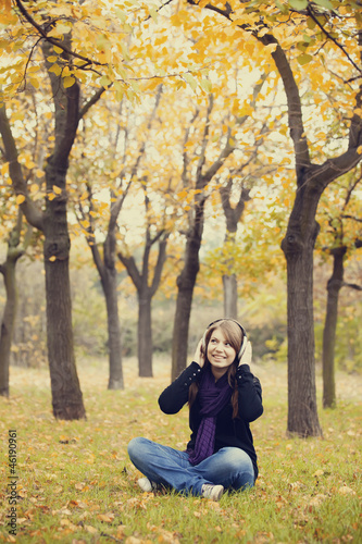 Young fashion girl with headphones at autumn park.
