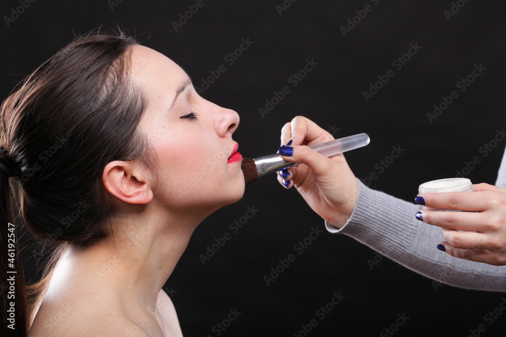 Obraz premium beautiful young brunette woman applying powder with a brush