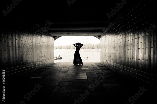 Silhouette of a girl on bright background in a tunnel