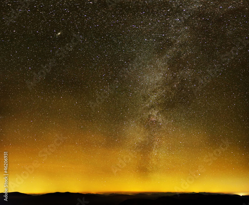 Obraz na płótnie Milky way over black mountains and city lights w salonie