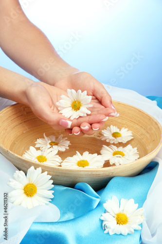 woman hands with wooden bowl of water with flowers,