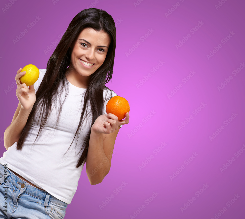 young pretty girl holding orange and lemon over pink background young pretty girl holding orange and lemon over pink background