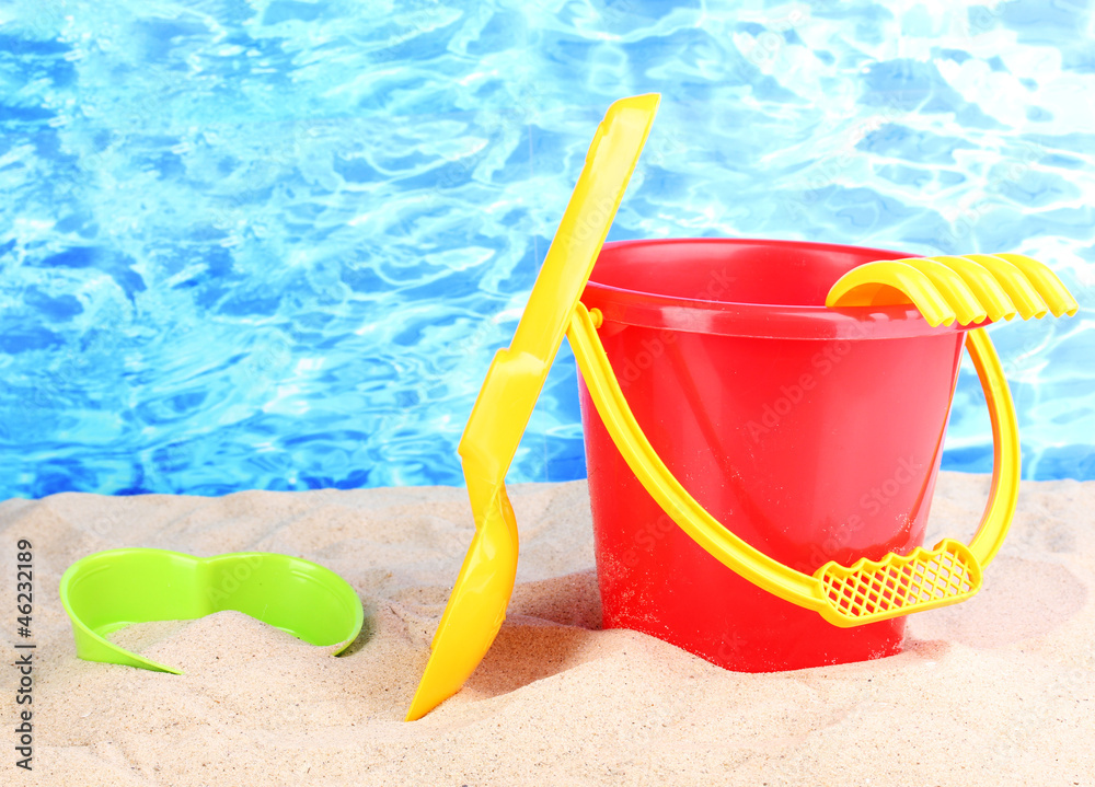 Children's beach toys on sand on water background Children's beach toys on sand on water background