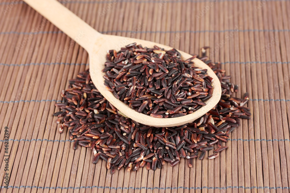 black rice in wooden spoon on bamboo mat black rice in wooden spoon on bamboo mat