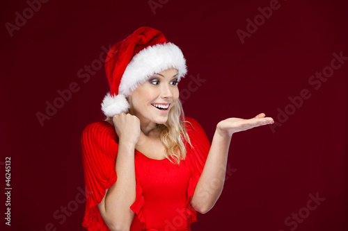Pretty girl in Christmas cap gestures palm up