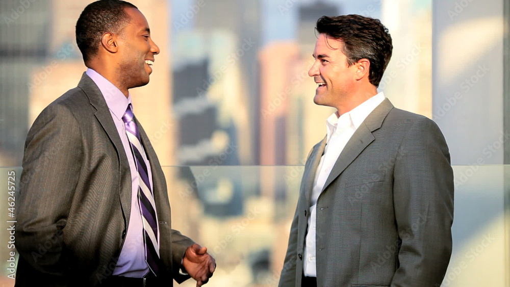 Handshake of multi ethnic managers talking business strategy on rooftop Handshake of multi ethnic managers talking business strategy on rooftop