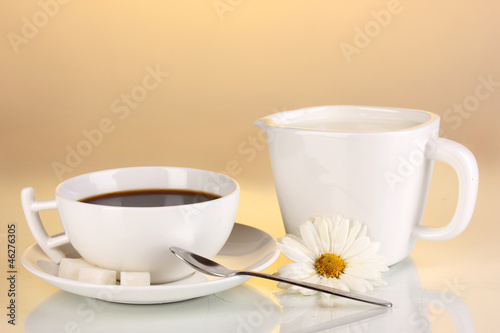 A cup of strong coffee and sweet cream on yellow background