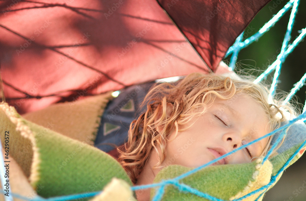 Child sleeps in a hammock in the garden.