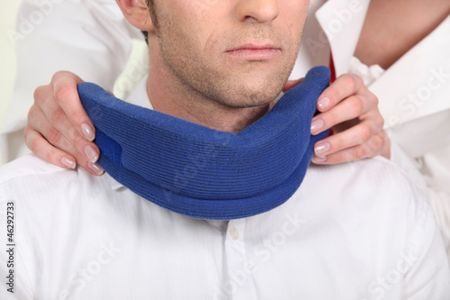 Nurse attaching a neck brace for a male patient