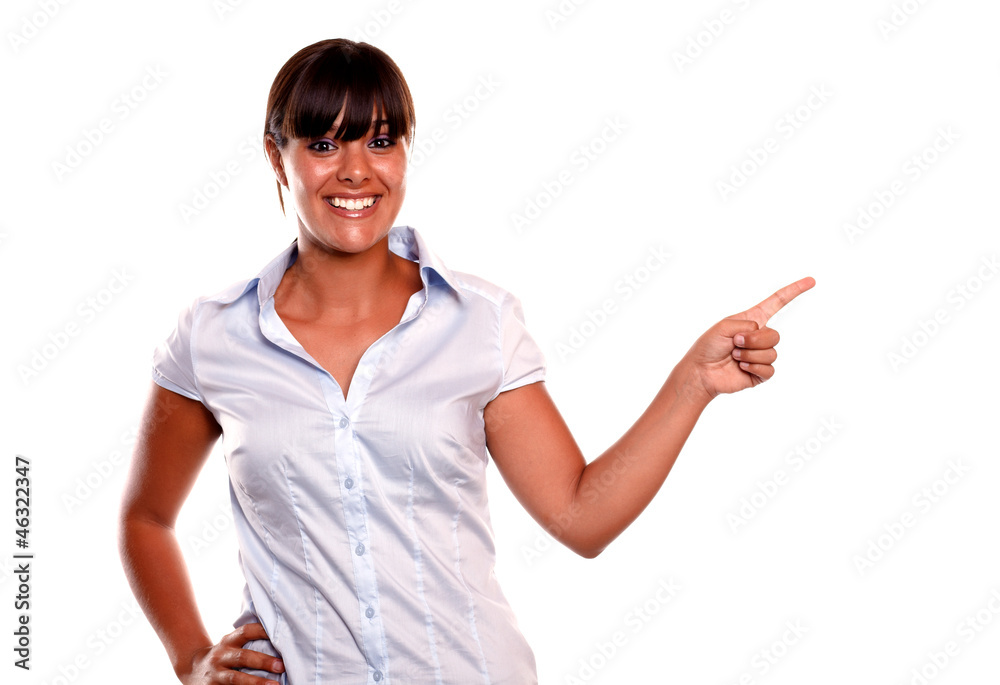 Smiling young woman looking at you pointing left Smiling young woman looking at you pointing left