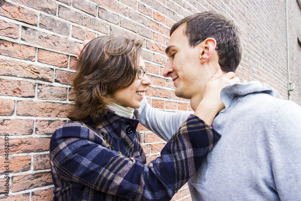 Portrait of love couple outdoor looking happy against wall backg