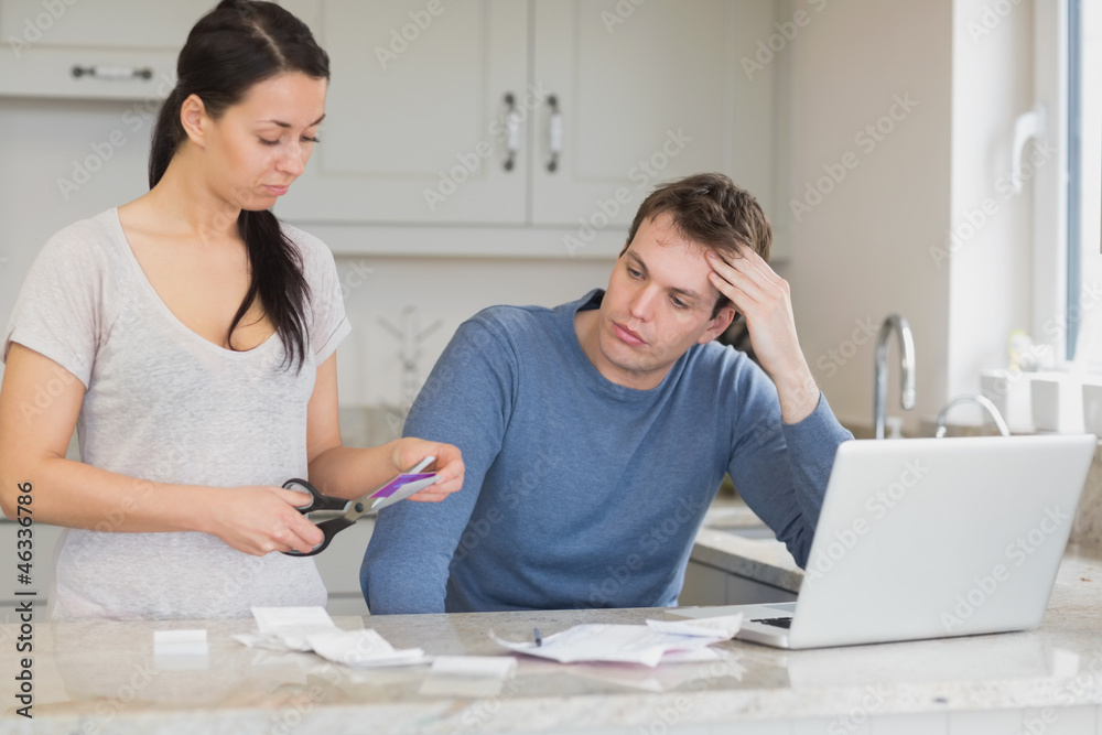 Wife cutting up credit card with husband watching Wife cutting up credit card with husband watching