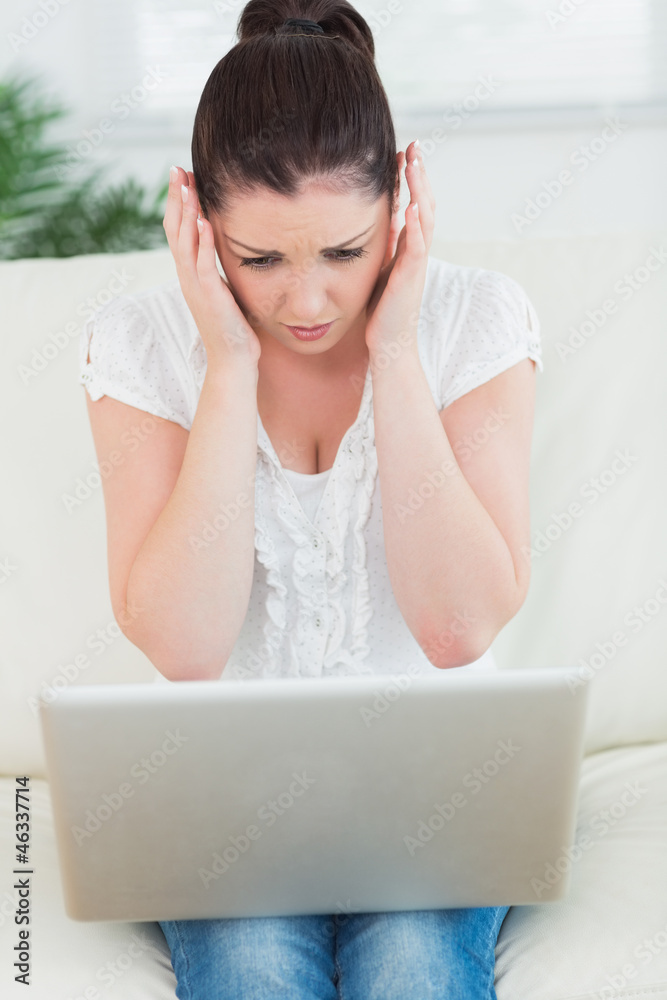 Overwhelmed woman on the couch using a laptop Overwhelmed woman on the couch using a laptop