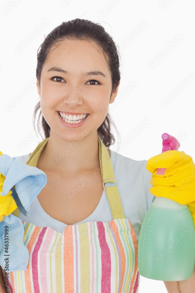 Happy woman holding spray bottle and rag