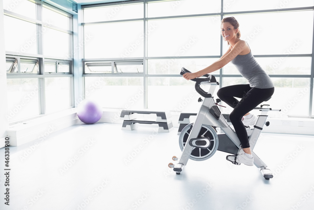 Fototapeta premium Happy woman riding an exercise bike