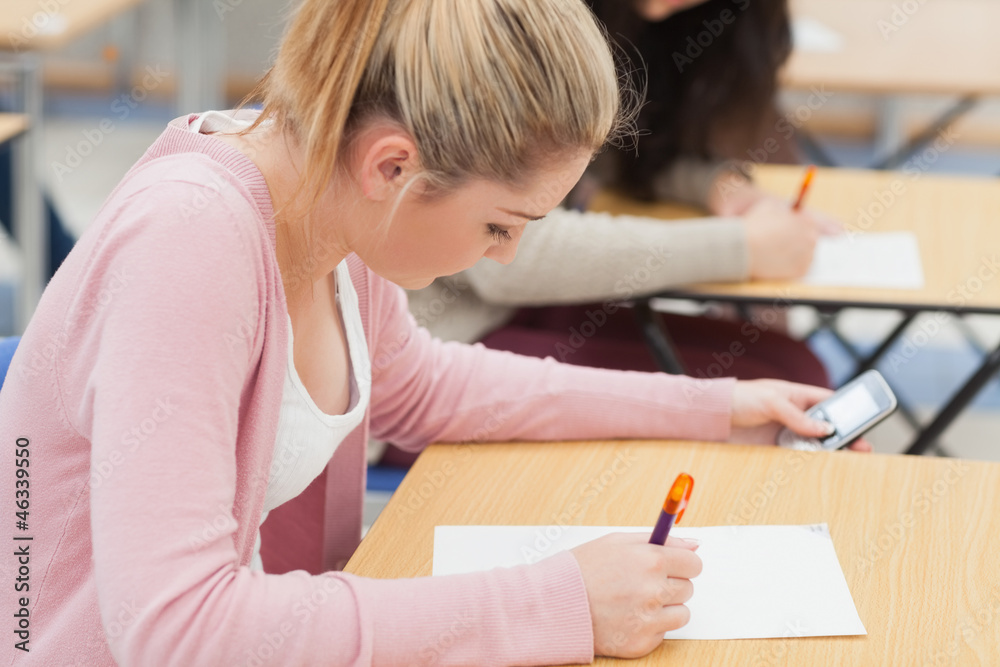 Girl is checking phone during exam Girl is checking phone during exam
