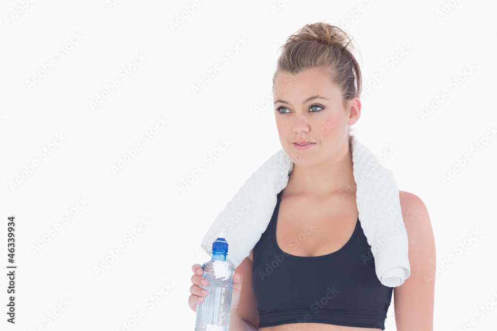 Woman standing holding a bottle of water and a towel Woman standing holding a bottle of water and a towel