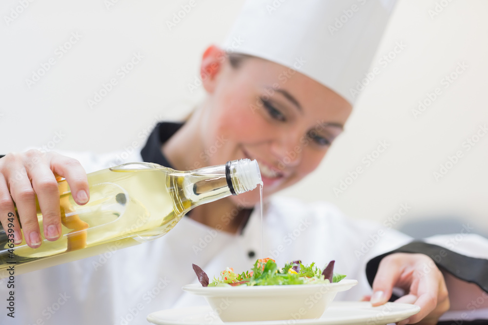 Smiling woman chef dressing a salad Smiling woman chef dressing a salad
