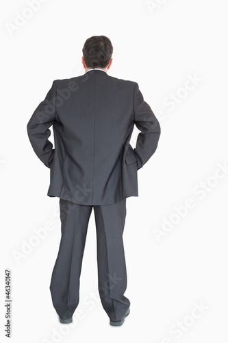 Businessman standing back to the camera with hands on hip
