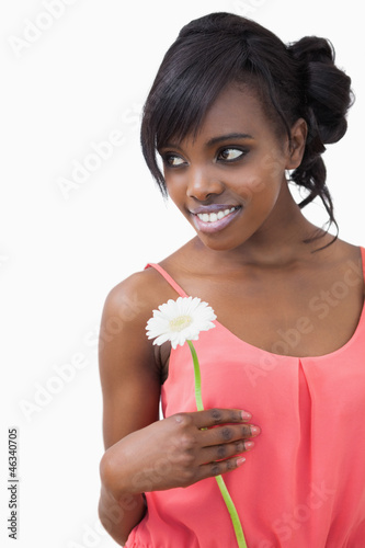 Girl standing holding a flower while smiling against white backg