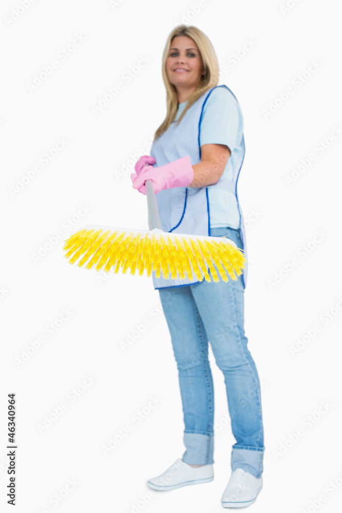 Smiling cleaner woman holding a yellow broom Smiling cleaner woman holding a yellow broom