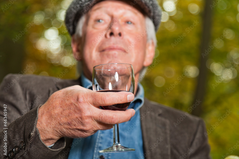 Senior man enjoying red wine in autumn forest. Senior man enjoying red wine in autumn forest.
