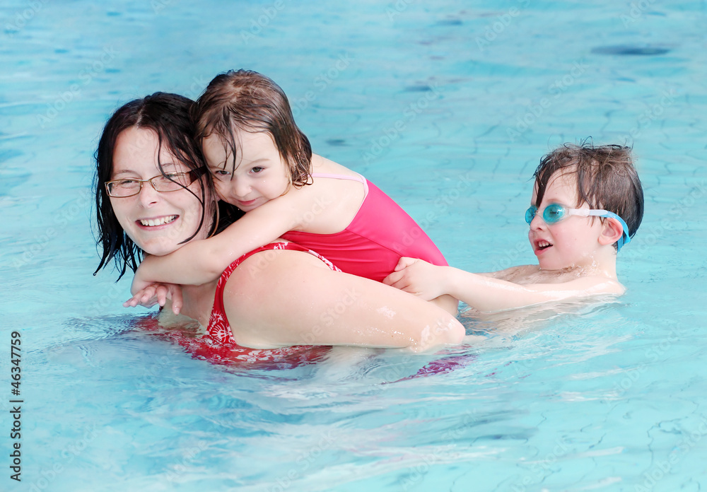 Happy family playing in a swimming pool.