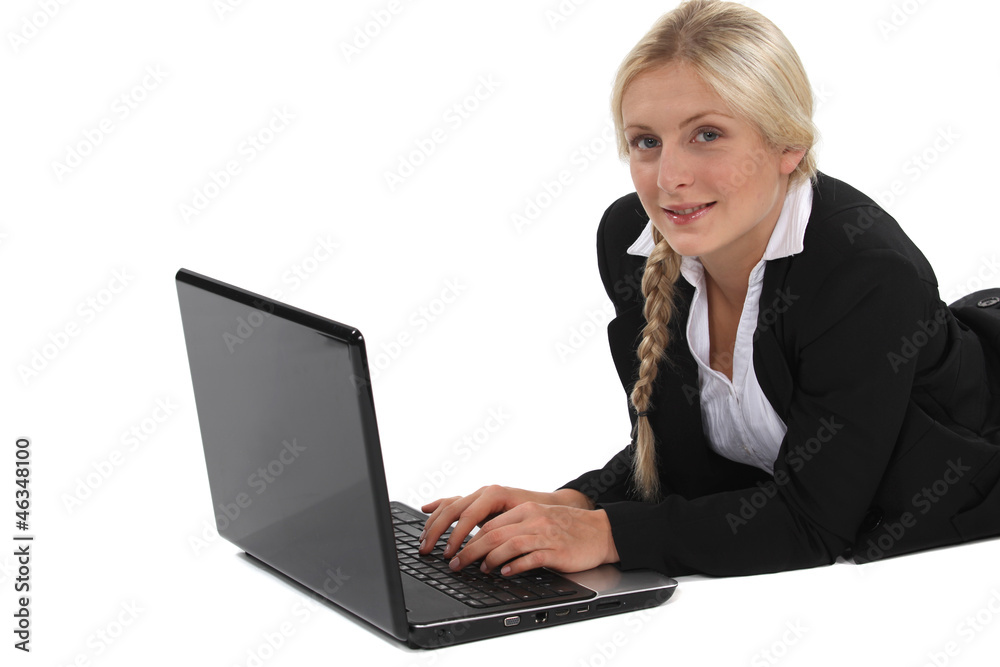 woman in a suit lying and working on her laptop woman in a suit lying and working on her laptop