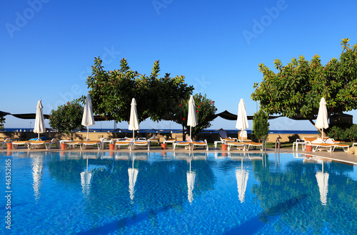 Swimming pool of luxury hotel with deckchairs photo