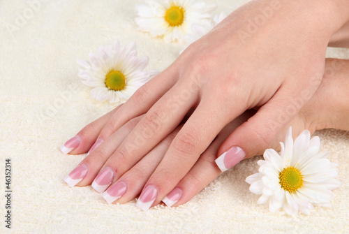 Woman hands with french manicure and flowers on towel