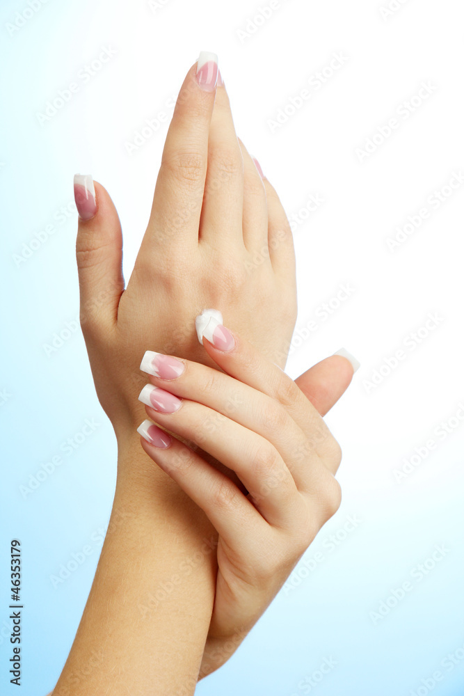 Beautiful woman hands with cream, on blue background