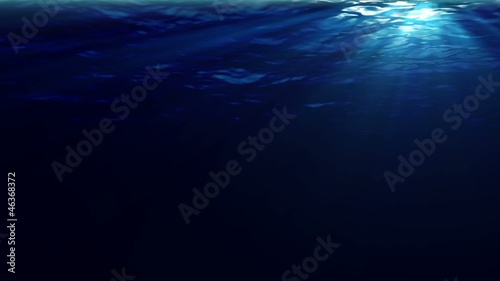Underwater sunrays shine through the water's surface. Looping.
