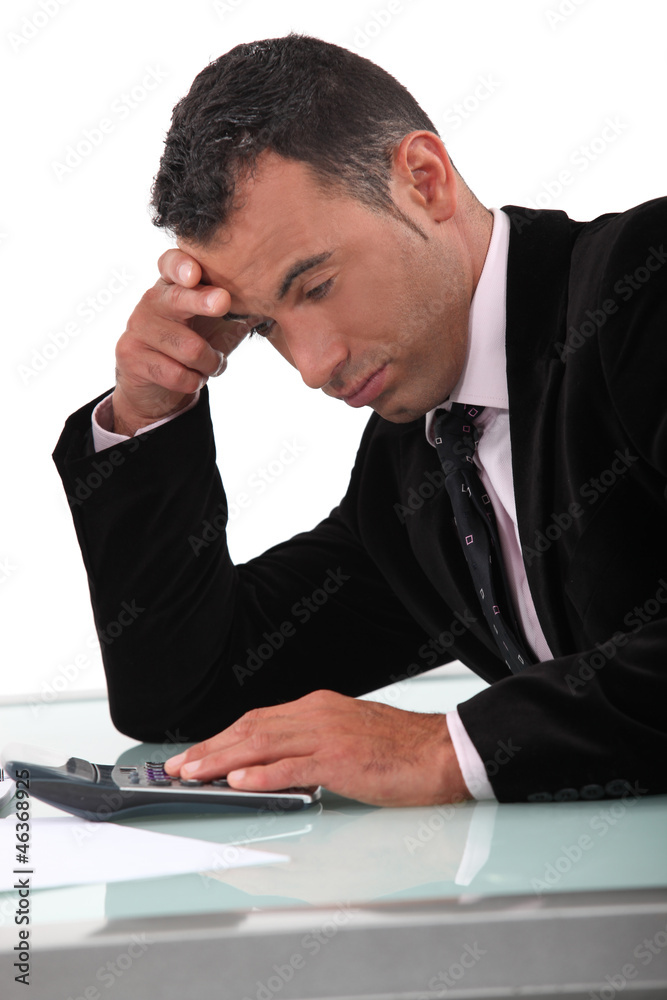 Jaded man using a calculator Jaded man using a calculator